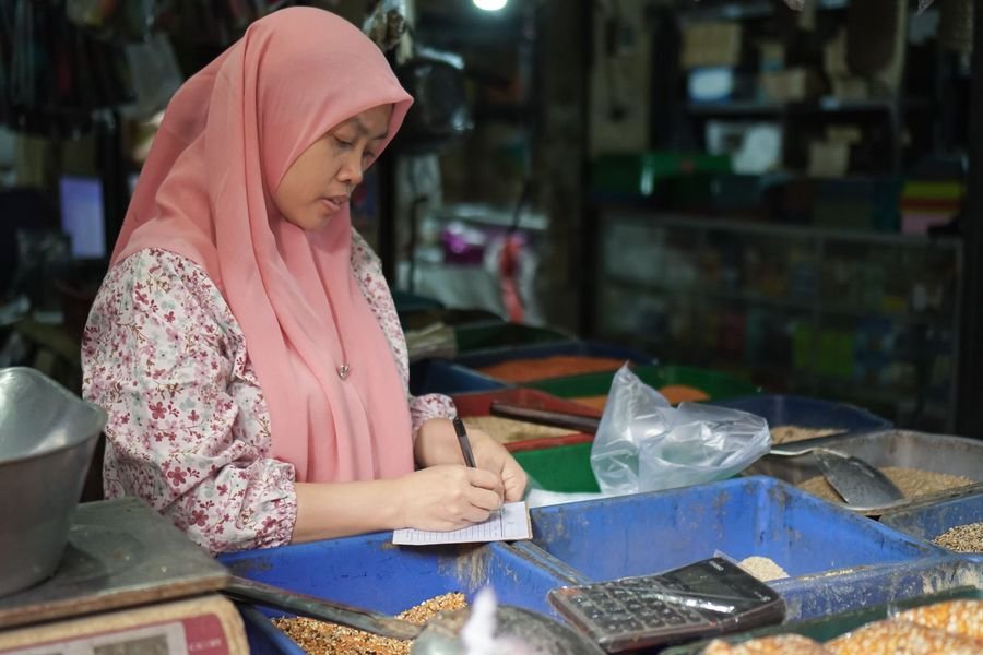 Pedagang mencatat pesanan secara manual di buku sebelum usahanya punya website