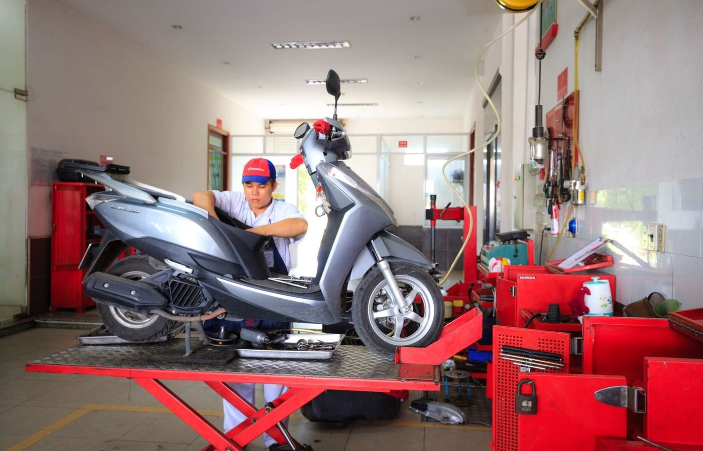 Mekanik Andi Motor memeriksa motor matic di atas lift bengkel yang bersih