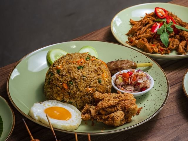 Nasi goreng kampung dengan telur mata sapi, ayam goreng, dan sate