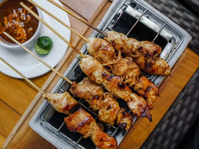 Sate ayam bumbu kacang sedang dibakar di atas arang