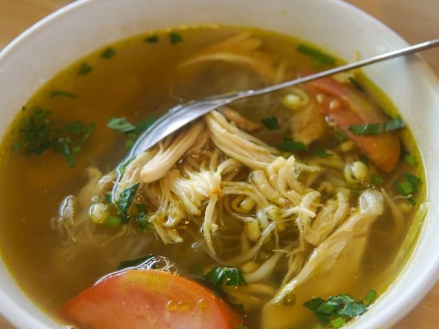 Semangkuk soto ayam kuning dengan tomat dan bihun