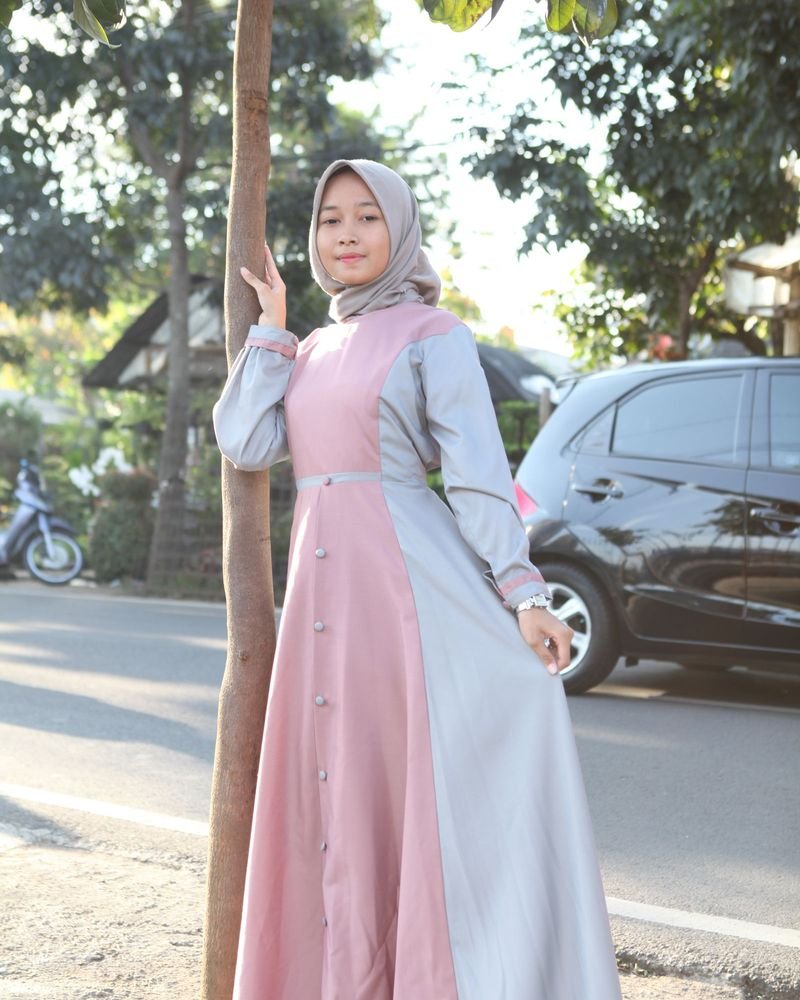 Model mengenakan Gamis Rania berpose di tepi jalan yang teduh
